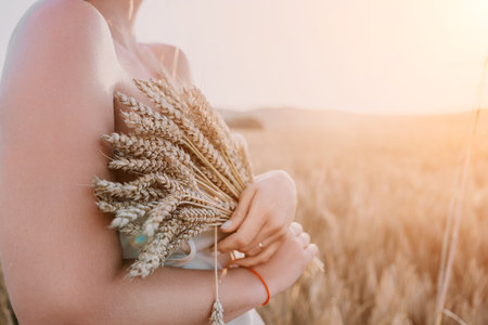 Woman wheat field. Agronomist, Woman farmer check golden ripe barley spikes in cultivated field. A woman is holding a bunch of wheat in her arms.の写真素材