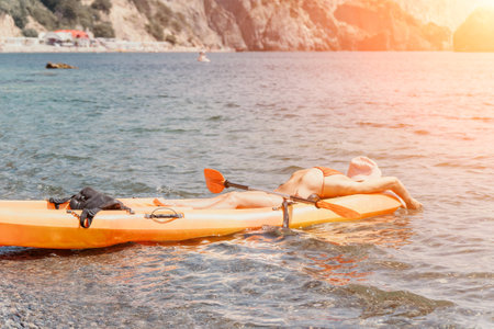 Kayaking, Sunset, Coast: Two people relaxing on a kayak at sunset near a rocky coast.の写真素材