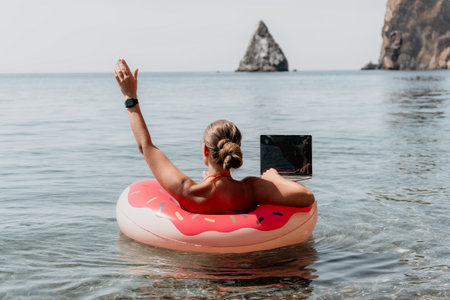 Woman, Beach, Laptop - Working remotely on a beach while floating on a donut tube.の写真素材