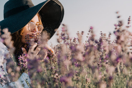 Woman in a Wide-Brimmed Hat Smelling Lavender Flowersの写真素材