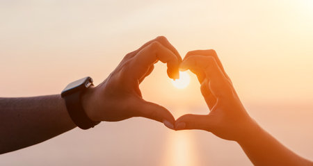Silhouetted Hands Form a Heart at Sunset