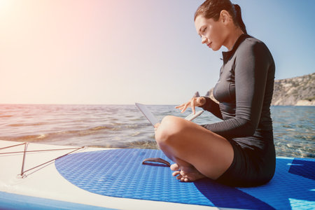 Woman Paddleboard Yoga Ocean Meditation - A woman in a wetsuit sits in a meditative pose on a paddleboard in the ocean.の写真素材