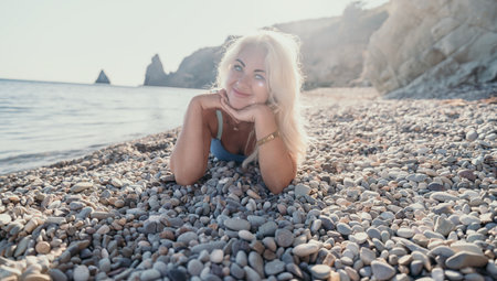 Blonde Woman Lying on a Pebble Beachの写真素材