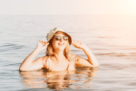 Woman, Beach, Water - Happy woman wearing sunglasses and a hat in the ocean.の写真素材