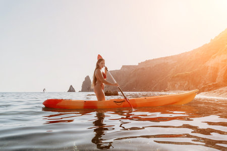 Woman Kayak Paddle Ocean - Woman paddling a kayak in the ocean near a rocky cliff.の写真素材
