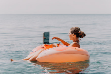 Woman Laptop Flamingo Float Ocean Beach Work Remotelyの写真素材