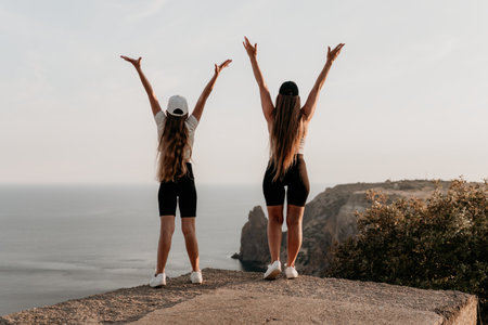 Two Women with Arms Raised in Triumph on a Cliffsideの写真素材