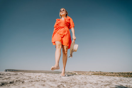 Woman in Orange Dress Walking on a Cliffの写真素材