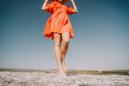 Woman in Orange Dress Walking on a Cliffの写真素材