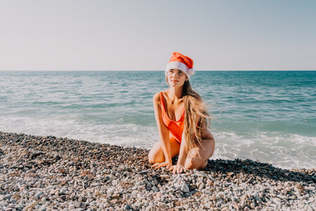 Christmas at the Beach: Woman in Santa Hat on the Coastの写真素材