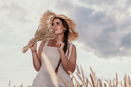 Woman wheat field. Agronomist, Woman farmer check golden ripe barley spikes in cultivated field. A woman is holding a bunch of wheat in her arms.の写真素材