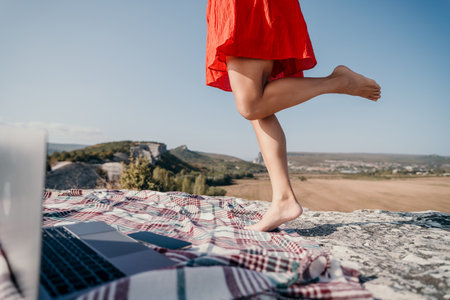 Woman in a Red Dress Stepping on a Blanket with a Laptopの写真素材