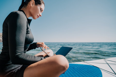 Woman Laptop Ocean Work Remotely - Working on a Laptop While Sitting on a Boat on the Ocean.の写真素材