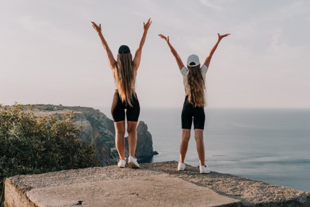 Two Women with Arms Raised, Back to Camera, Enjoying the Viewの写真素材