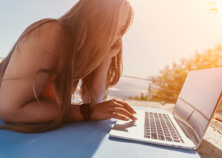 Woman Working on Laptop by the Water on a Sunny Dayの写真素材