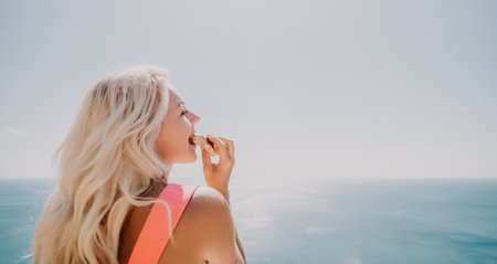Blonde Woman Enjoying a Snack by the Oceanの写真素材