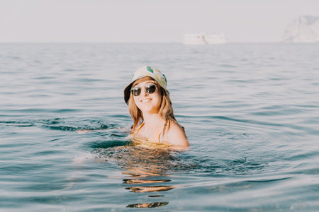 Woman Hat Sunglasses Water - Woman wearing a hat and sunglasses while swimming in the sea.の写真素材