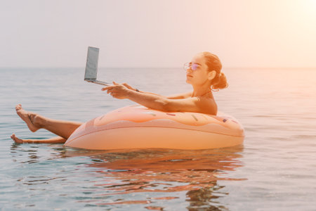Woman Laptop Beach - Relaxing on an inflatable ring in the ocean while using a laptop.の写真素材