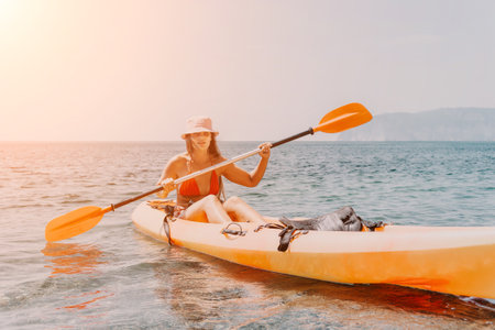 Kayaking Woman Sea Sunset - Young woman paddling kayak in the ocean at sunset.の写真素材