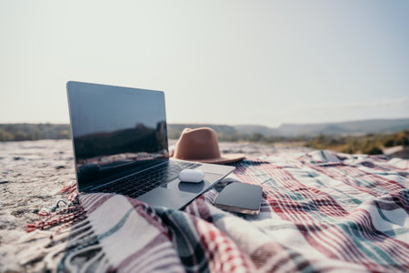 Laptop, Hat, and Phone on a Plaid Blanket in Natureの写真素材