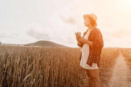 Woman wheat field. Agronomist, Woman farmer check golden ripe barley spikes in cultivated field. Closeup of female hand on plantation in agricultural crop management concept. Slow motionの写真素材