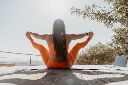 Woman Practicing Yoga Outdoors with a Laptopの写真素材