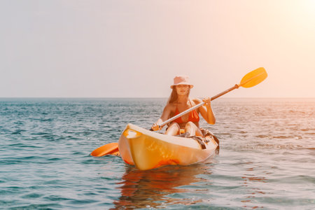 Kayaking Woman Sea Sunset - A woman in a kayak paddles through the sea at sunset, enjoying a peaceful and scenic adventure.の写真素材