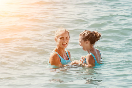Two Women Laughing in the Sea on a Sunny Dayの写真素材