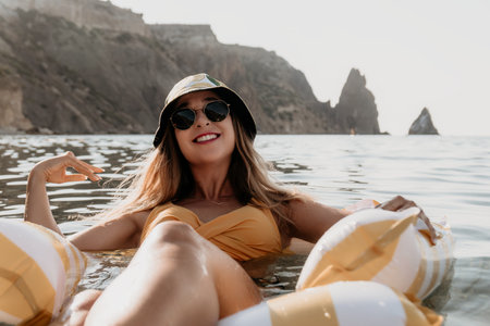 Woman, Beach, Relaxation: Smiling woman in a yellow swimsuit relaxes on a float in the ocean.