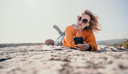 Relaxed Woman on a Clifftop with a Phoneの写真素材