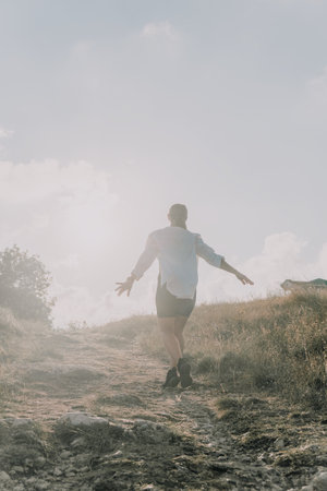 Man Hiking Trail Mountain Landscape - A man walks a trail on a mountain with a bright sky in the background.の写真素材