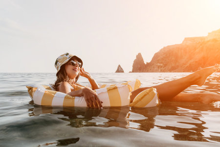 Woman, Beach, Float - Relaxing on a yellow and white striped float in the ocean near rocky cliffs.