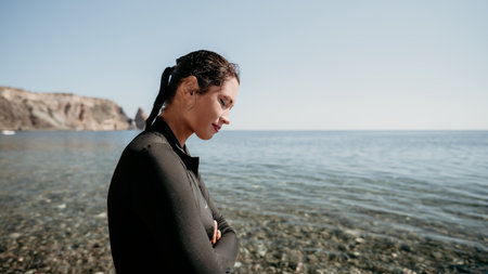 Woman Beach Sea - A woman stands on a beach with her back to the camera, looking out at the sea.の写真素材