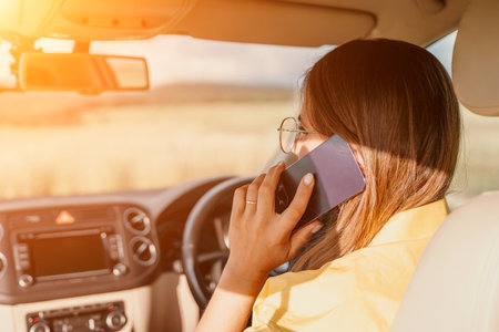 Happy woman talking on the phone while sitting in the car on nature Relaxed video call, professional conversation, female executive in automobile. business woman talking on video call on phone.の写真素材