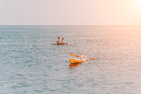 Two people row a small boat on a calm ocean during sunset.