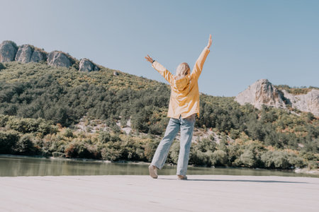 Woman in Yellow Jacket Raising Her Arms on a Wooden Pier