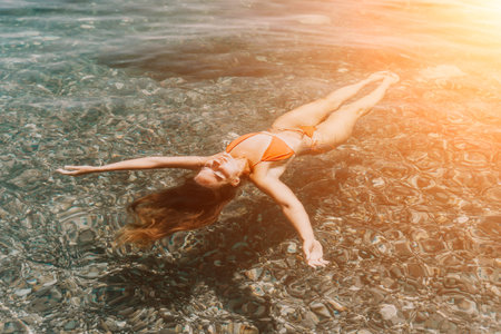 Woman, Ocean, Bikini: Underwater view of a woman floating on her back in the ocean wearing a bikini.の写真素材