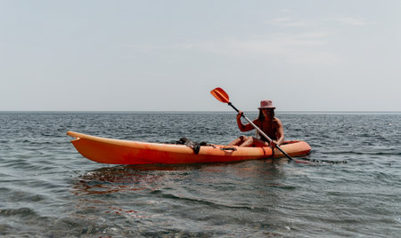 Kayaking Woman Ocean - Woman paddling kayak on calm ocean water during cloudy day.