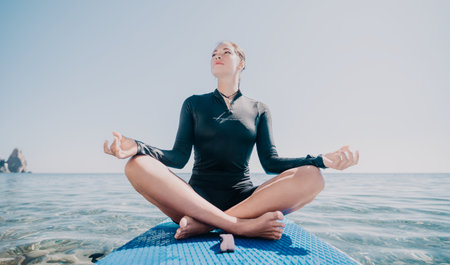 Yoga, Beach, Meditation - Woman practices yoga on a blue mat in the ocean.