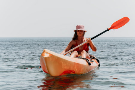 Kayaking Woman Paddle Ocean - A woman in a pink hat kayaks on the ocean while holding a paddle.の写真素材