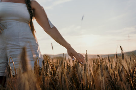 Woman Reaches Out to Wheat Field at Sunsetの写真素材