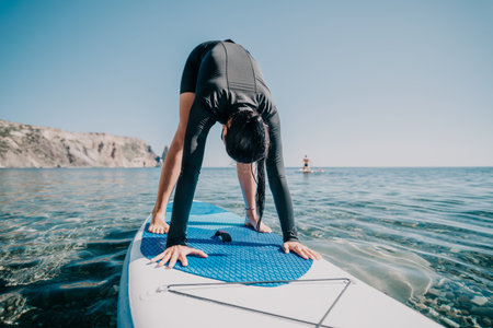Yoga Paddleboard Water Exercise Greece - Woman doing yoga on a paddleboard in the Aegean Sea near Santorini, Greece.の写真素材