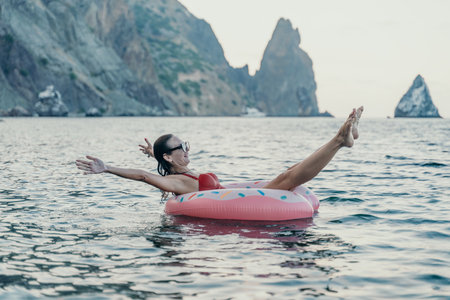 Woman swimming vacation, happy woman floats on an inflatable donut in mountain sea.の写真素材