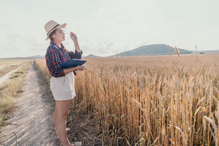 Young Woman Inspecting Wheat Field in Summer