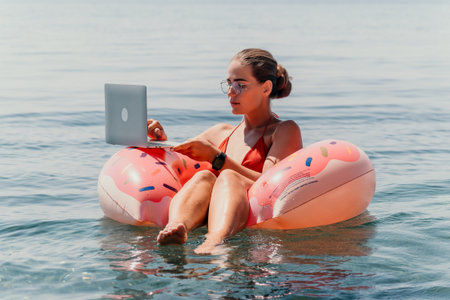 Woman Working on Laptop While Relaxing on a Floatの写真素材