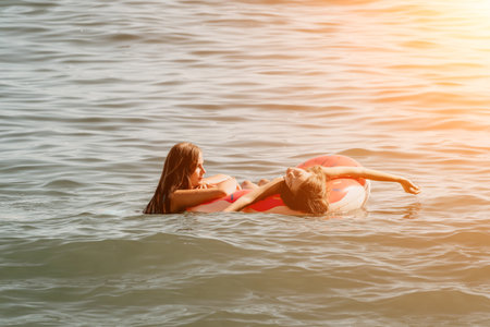 Two Young Women Relaxing on a Donut Float in the Oceanの写真素材
