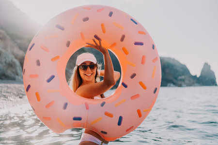 Woman, donut, sea, happy woman enjoys summer vacation in the ocean with an inflatable ring
