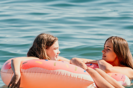 Two Women Relaxing in a Pink Inflatable Donut Ring on a Sunny Day