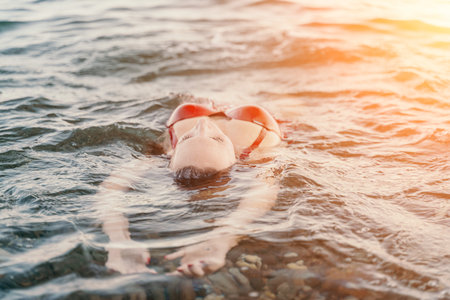 Woman floating ocean young woman floating peacefully on her back in the ocean during summer vacationの写真素材
