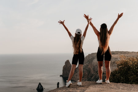 Two Women Embracing the Sunset on a Clifftopの写真素材